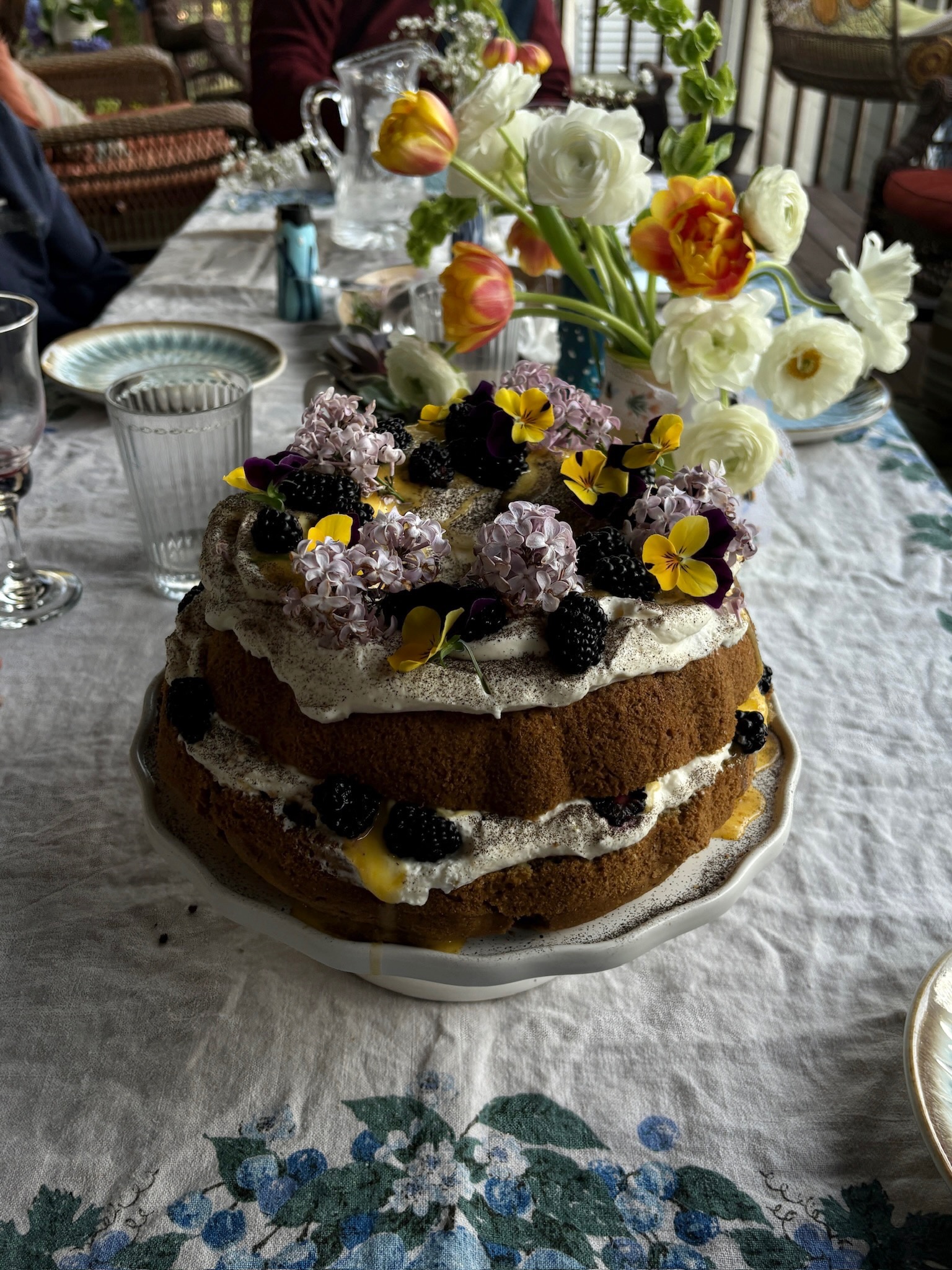 Rustic naked cake with lilacs and blackberries on garden table